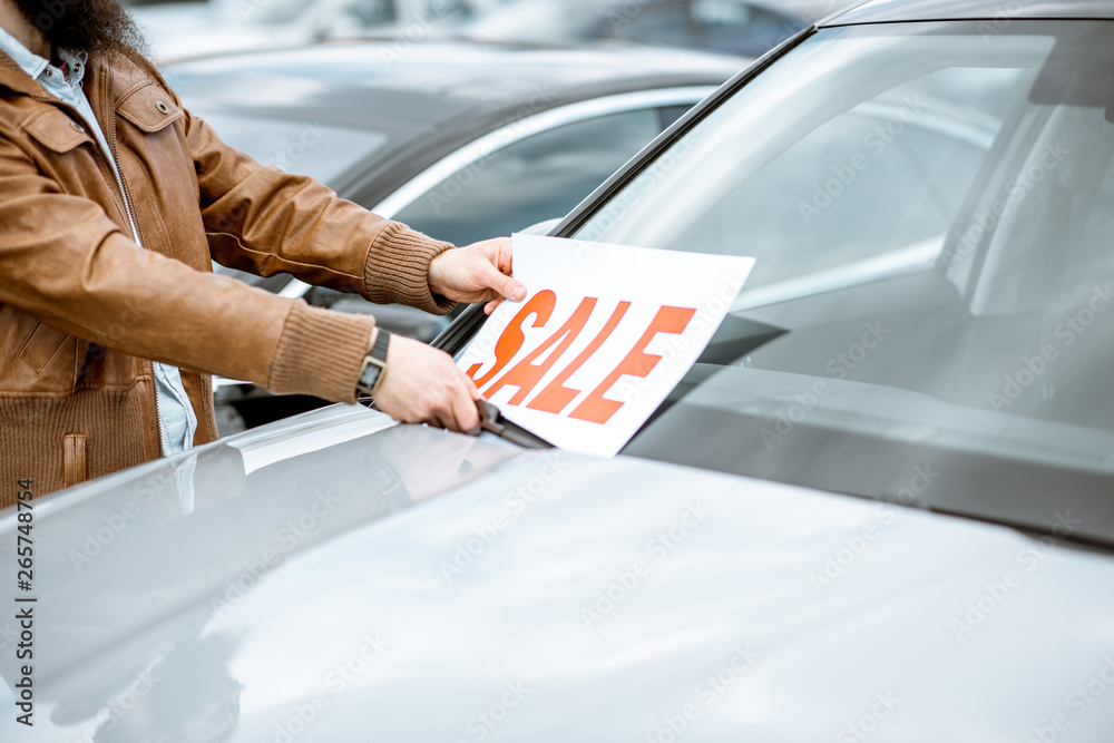 Salesperson putting sale plate on the car windshield on the open ground of a dealership, close-up vi