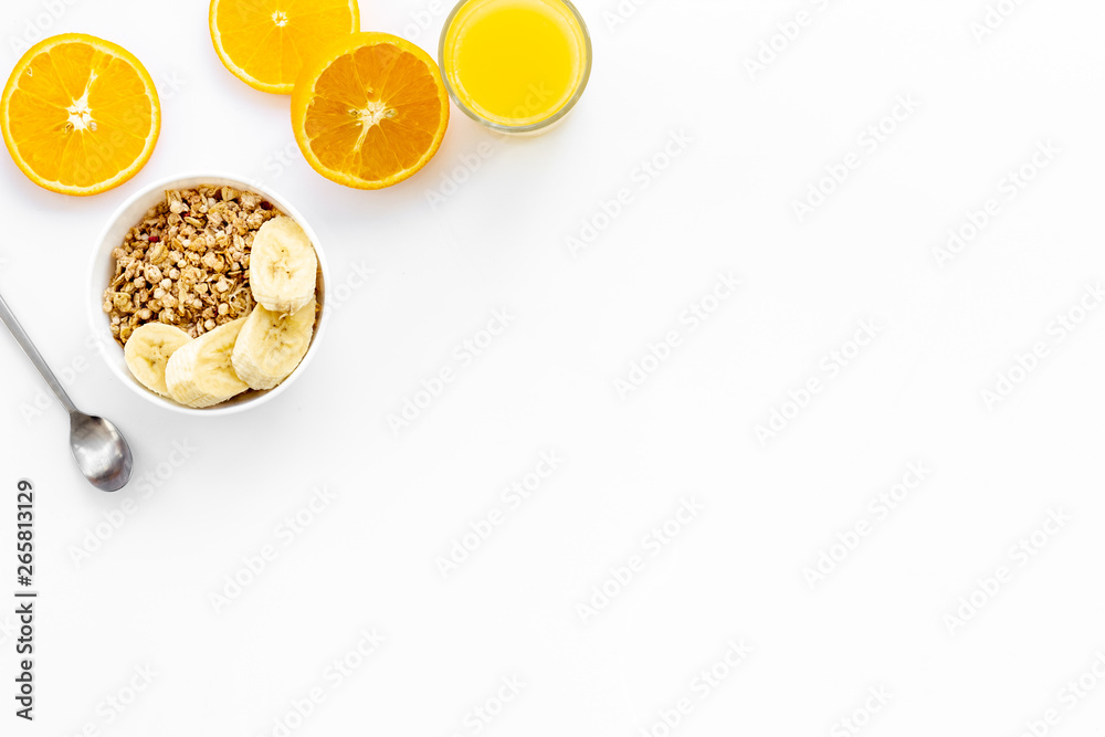 granola with banana slices and orange juice for breakfast on blue background top view copyspace