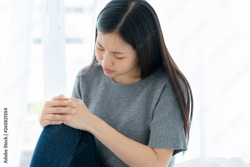 unhappy asian woman touch leg knee with hurt and injure white background