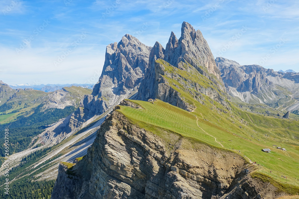 AERIAL: Steep grassfields extend up to the base of the rocky mountain range.