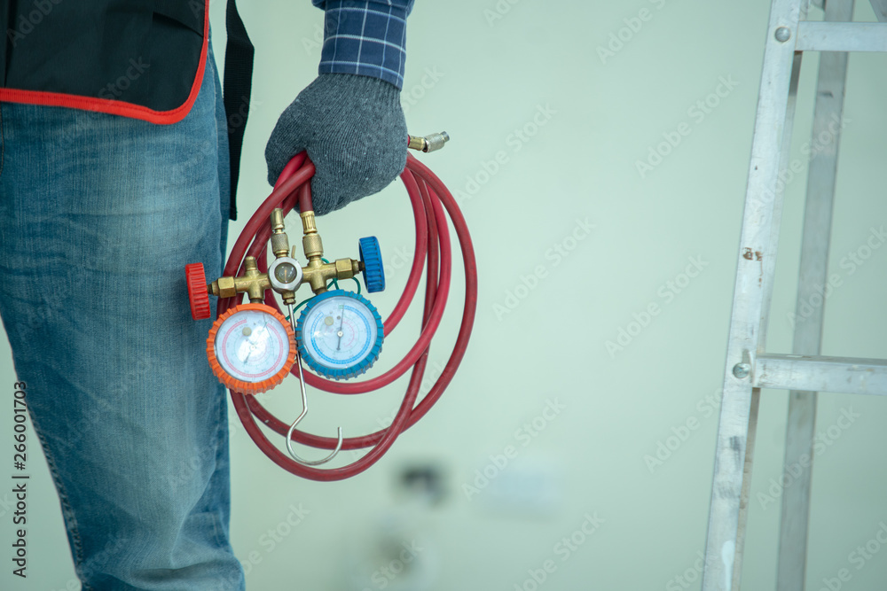 The technician is checking the air system,measuring equipment for filling air conditioners.