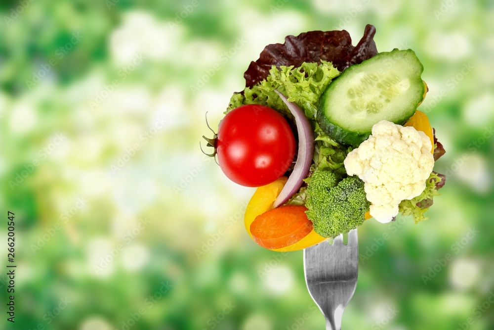 Fresh raw vegetables on fork on blue background