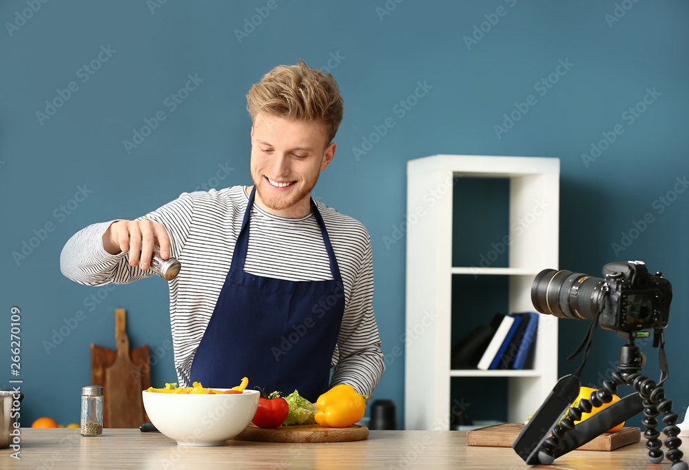 Young male food blogger recording video in kitchen