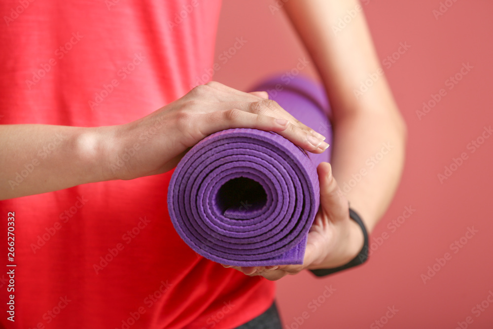 Young sporty woman with yoga mat on color background, closeup