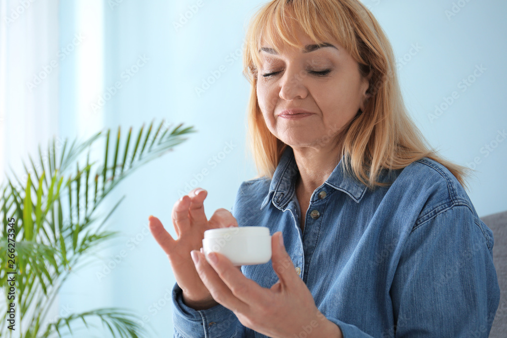 Mature woman with jar of cream at home