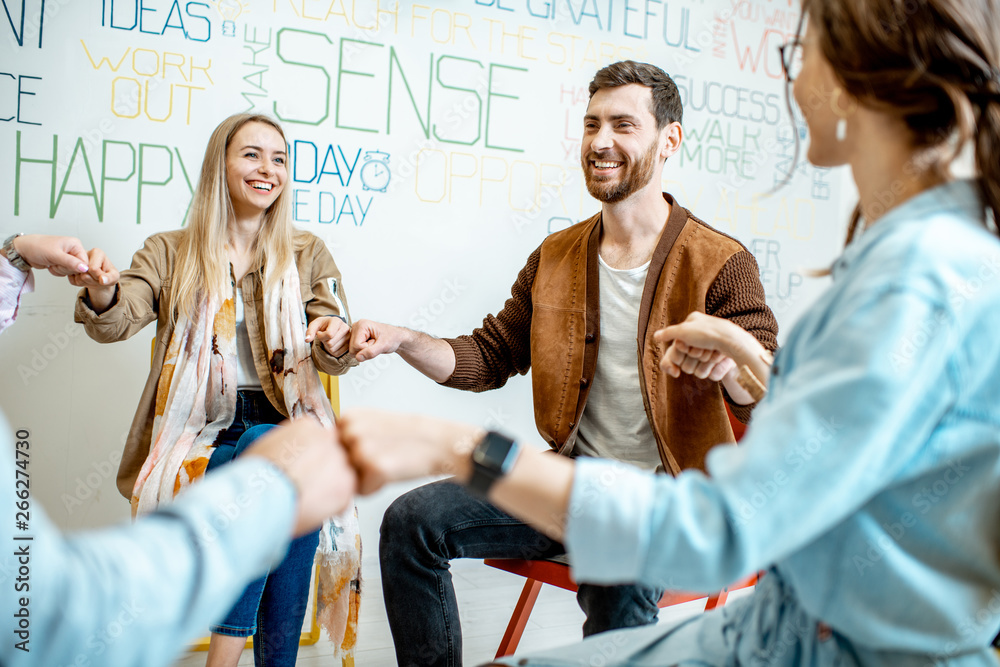 Group of diverse people keeping hands together, sitting in a circle during the psychological therapy