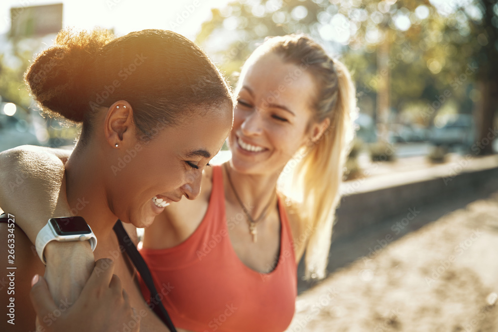 Two friends in sportswear laughing after an outdoor workout toge