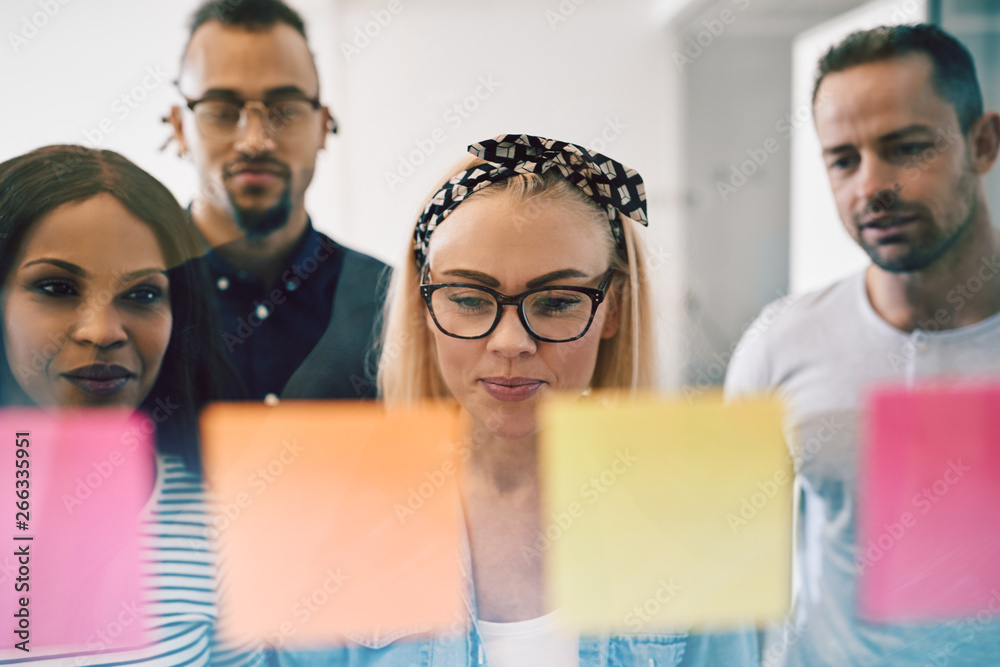 Smiling colleagues brainstorming with sticky notes on an office