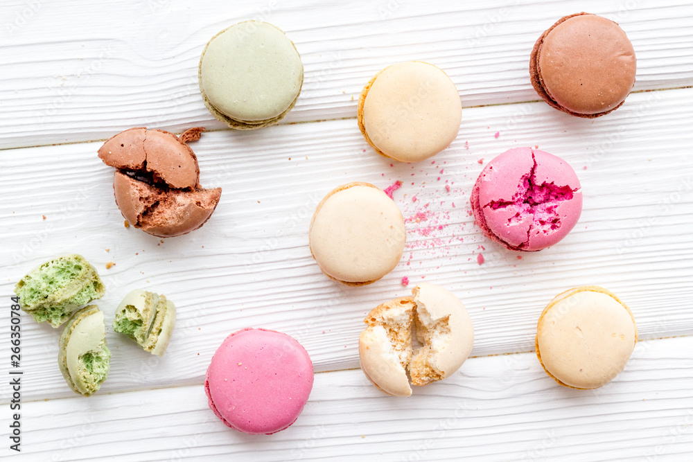 Brignt macarons for sweet break on white wooden background top view pattern