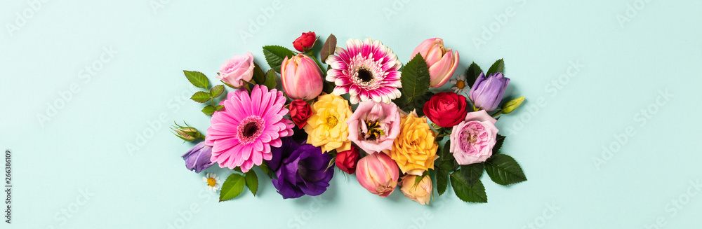 Creative layout made with beautiful flowers on blue background.