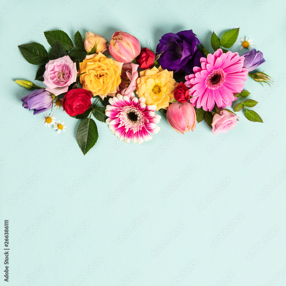 Creative layout made with beautiful flowers on blue background.