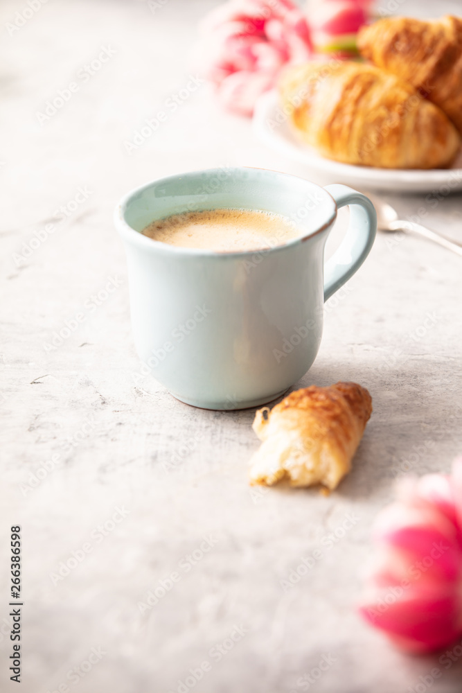 Morning coffee, croissants and spring tulips on light grey backg