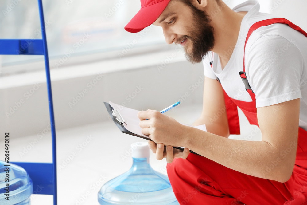 Delivery courier with bottles of water and clipboard in office