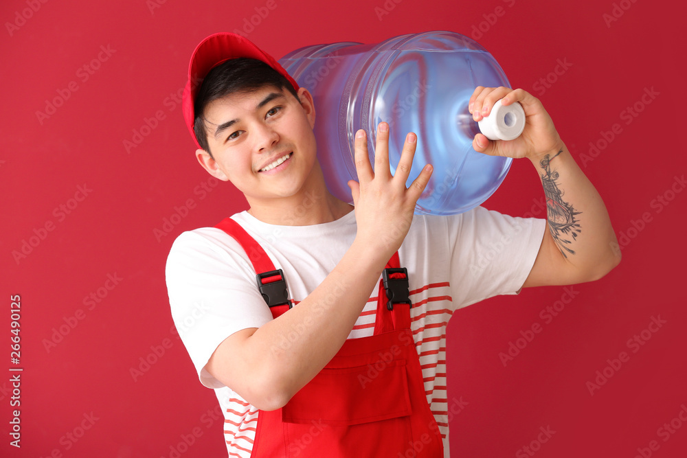 Asian delivery courier with bottle of water on color background