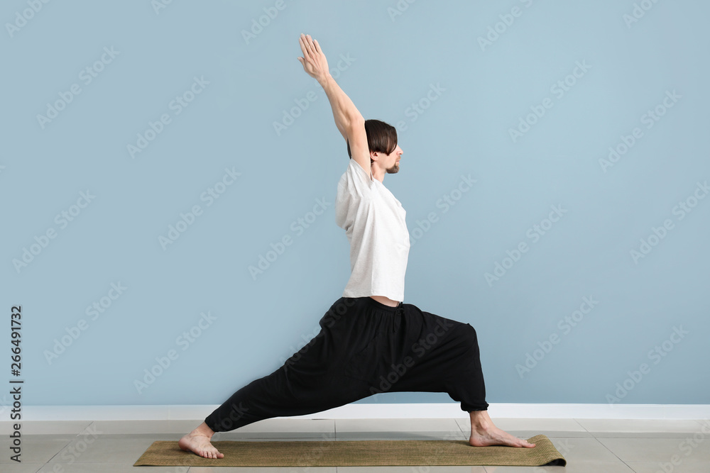 Sporty man practicing yoga indoors