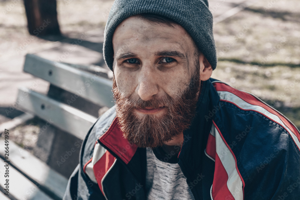 Poor homeless man sitting on bench outdoors