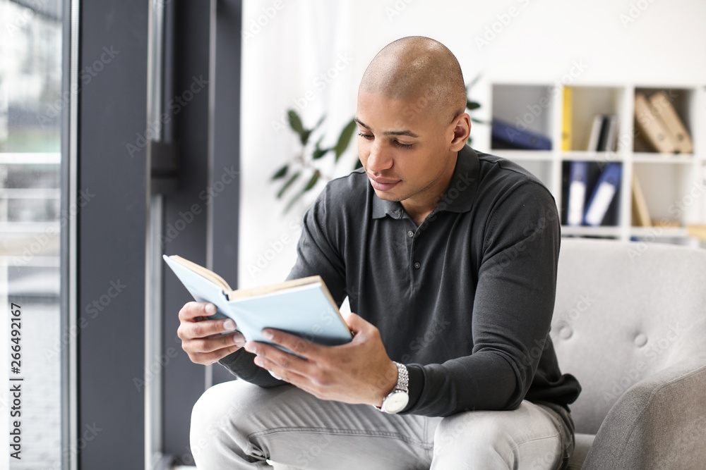 African-American man reading book at home