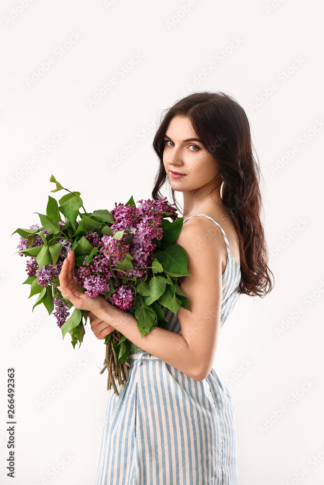 Beautiful young woman with bouquet of lilac flowers on white background