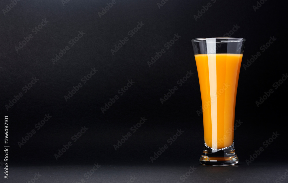 Glass of orange juice isolated on black background with copy space for text, fresh citrus cocktail