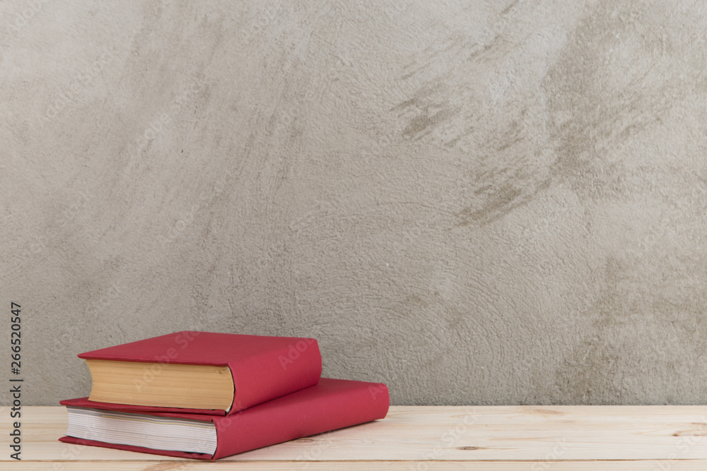 Education and reading concept - group of colorful books on the wooden table, concrete wall blackboar