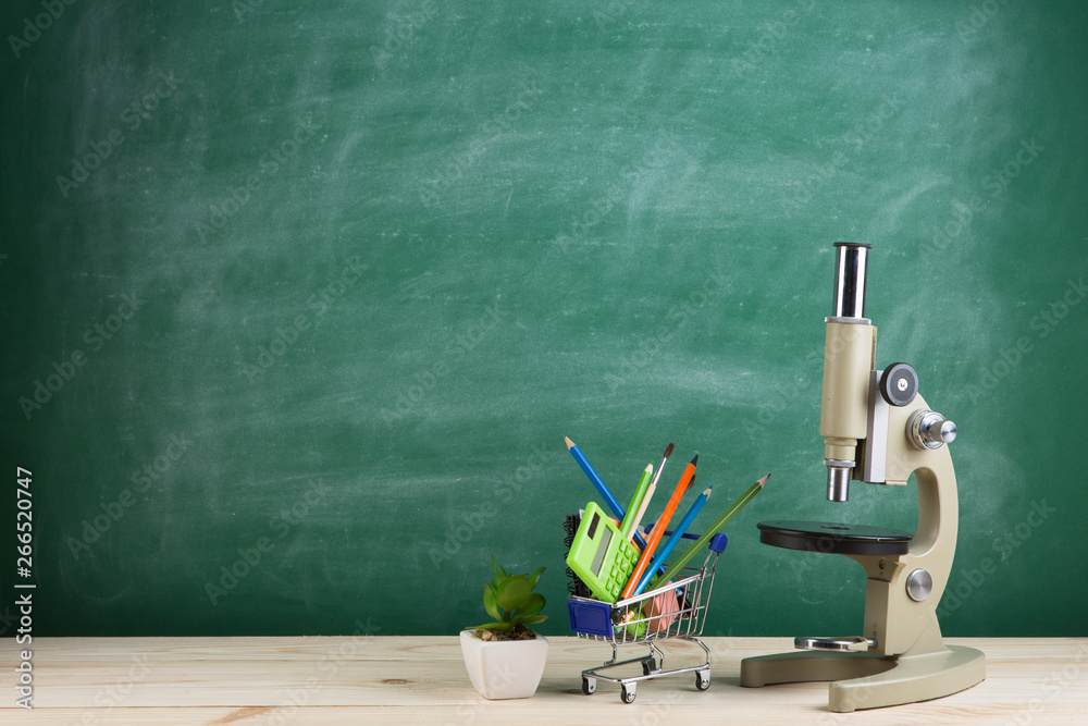 Education concept - microscope on the desk in the auditorium, blackboard background