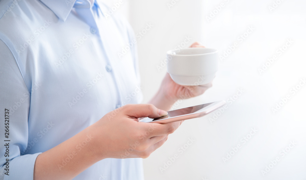 Side view of asia young business woman in blue shirt standing lying on the wall beside window drinki