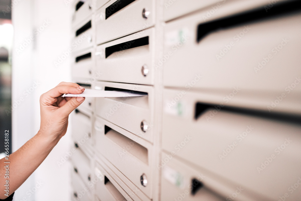 Posting a letter to apartment building mailbox.