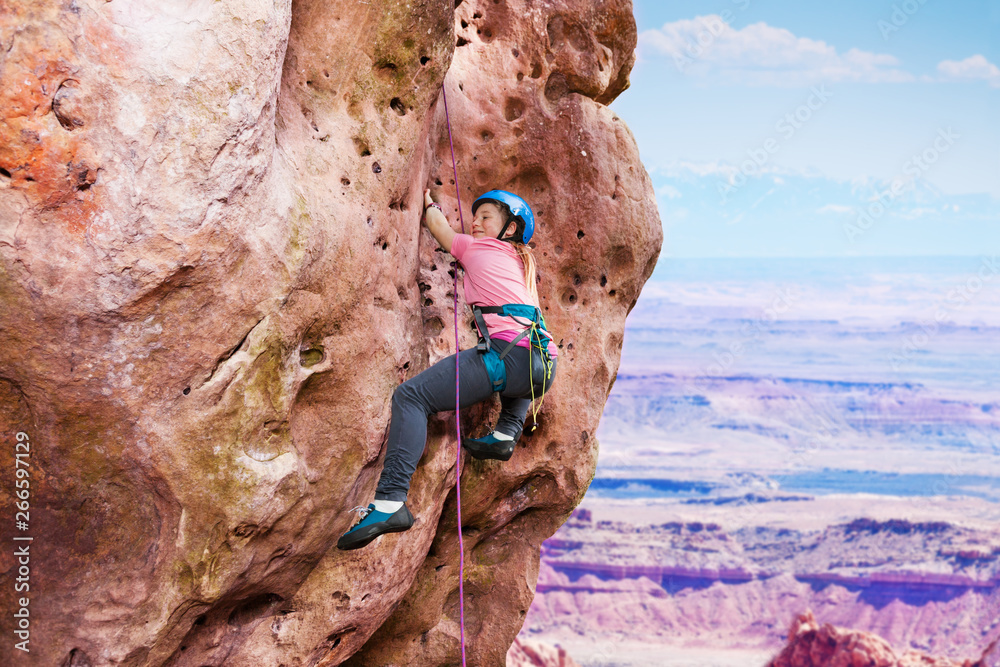 Girl rock climbing on summit of the mountain