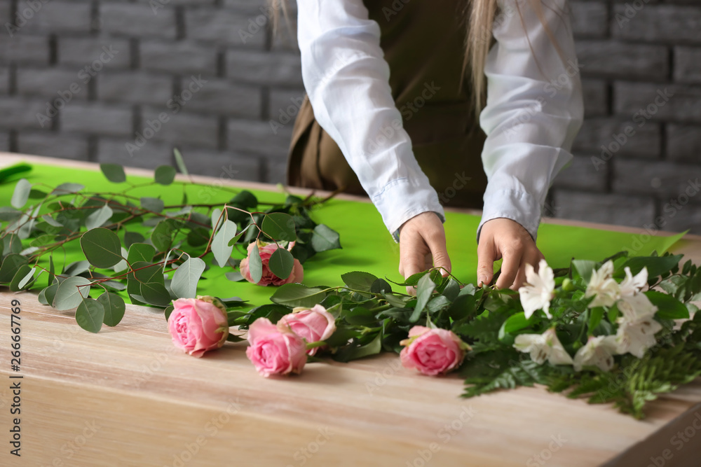 Florist making bouquet at table against dark background