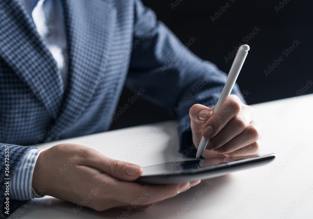 Man in business suit sitting at desk with tablet