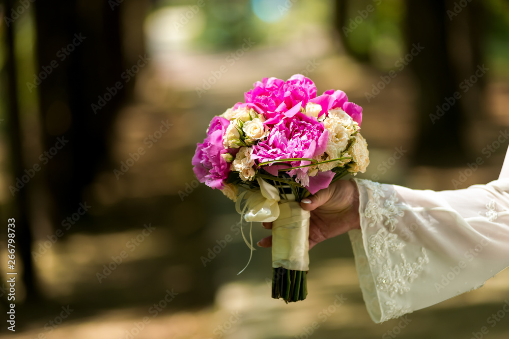 Wedding. The bride in a dress standing in a green garden and holding a bouquet