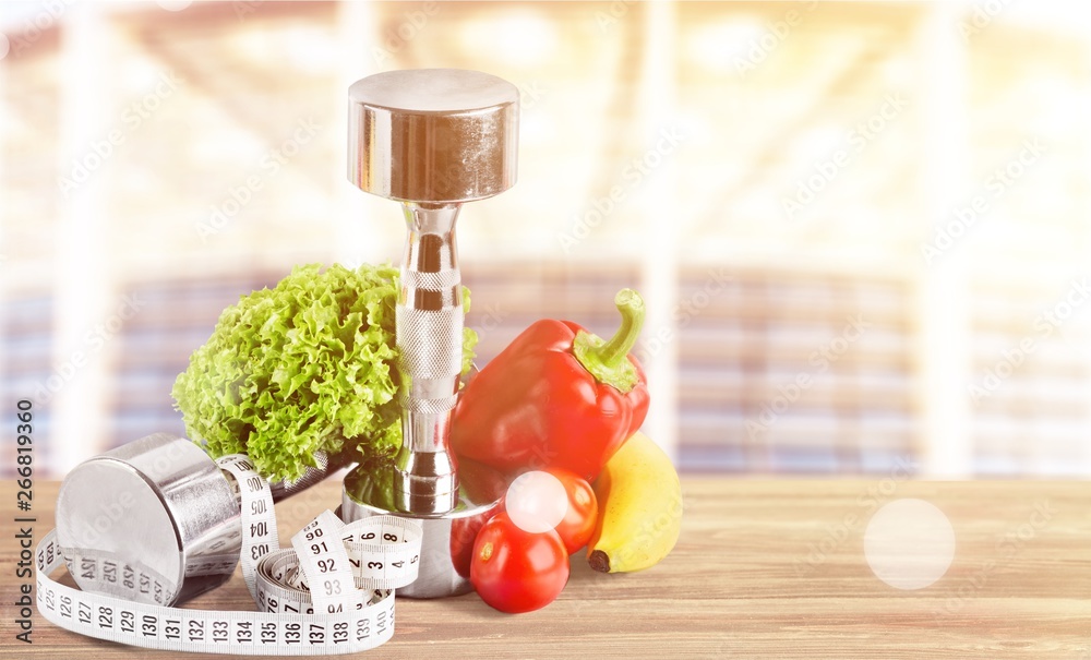 Dumbbells with bottled water , measuring tape and vegetables isolated on white background