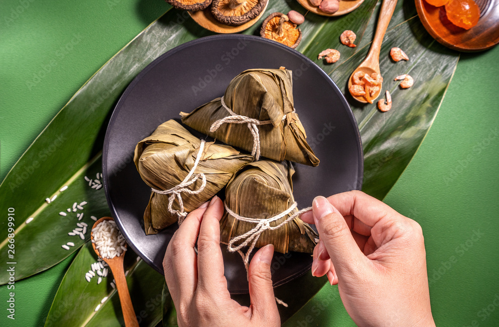 Zongzi, woman eating steamed rice dumplings on green table background, food in dragon boat festival 