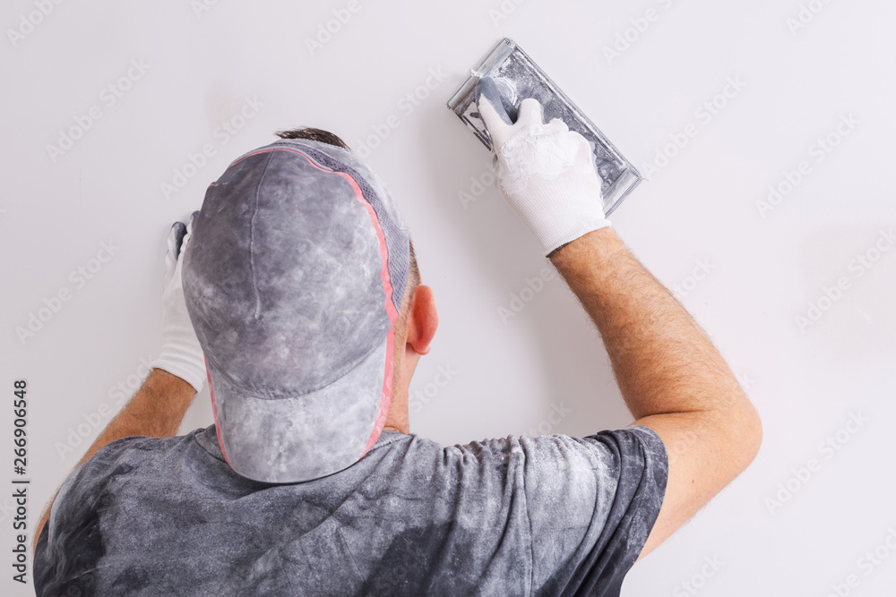 Plasterer polishing a gypsum wall. House renovation concept.