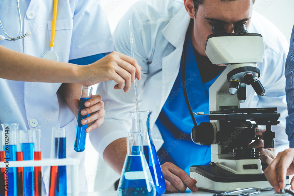 Group of scientists wearing lab coat working in laboratory while examining biochemistry sample in te