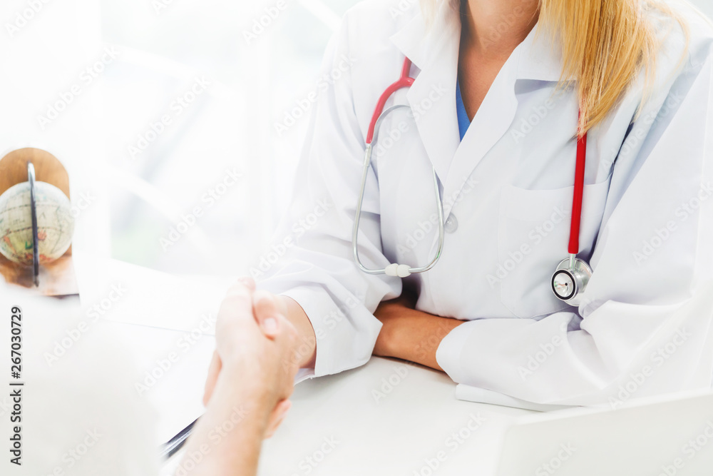 Woman doctor doing handshake with male patient in hospital office room. Healthcare and medical servi