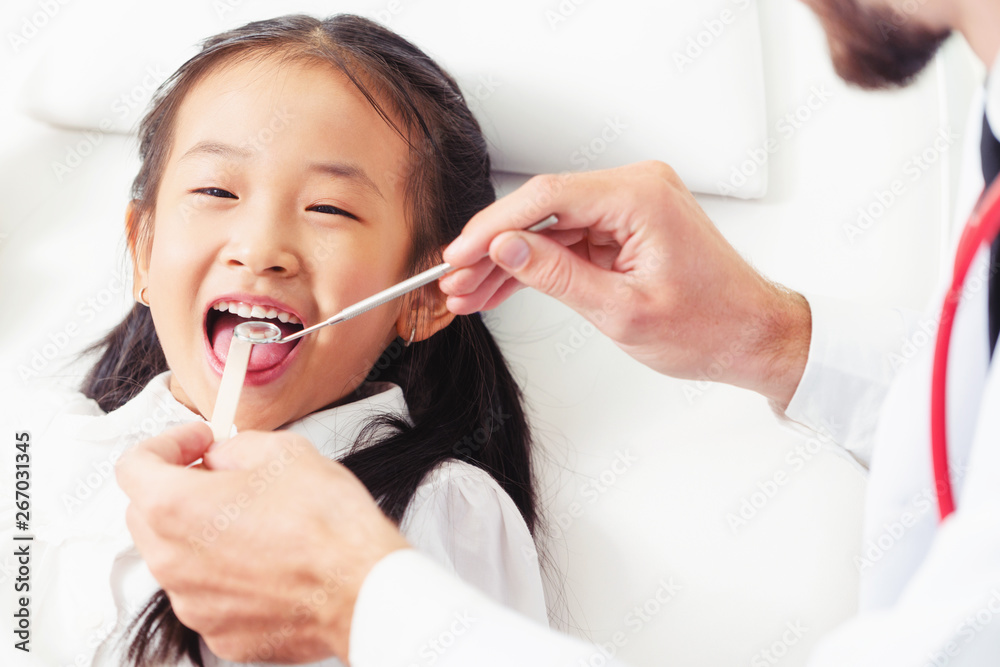 Friendly young dentist examining happy child teeth in dental clinic. Dentistry concept.