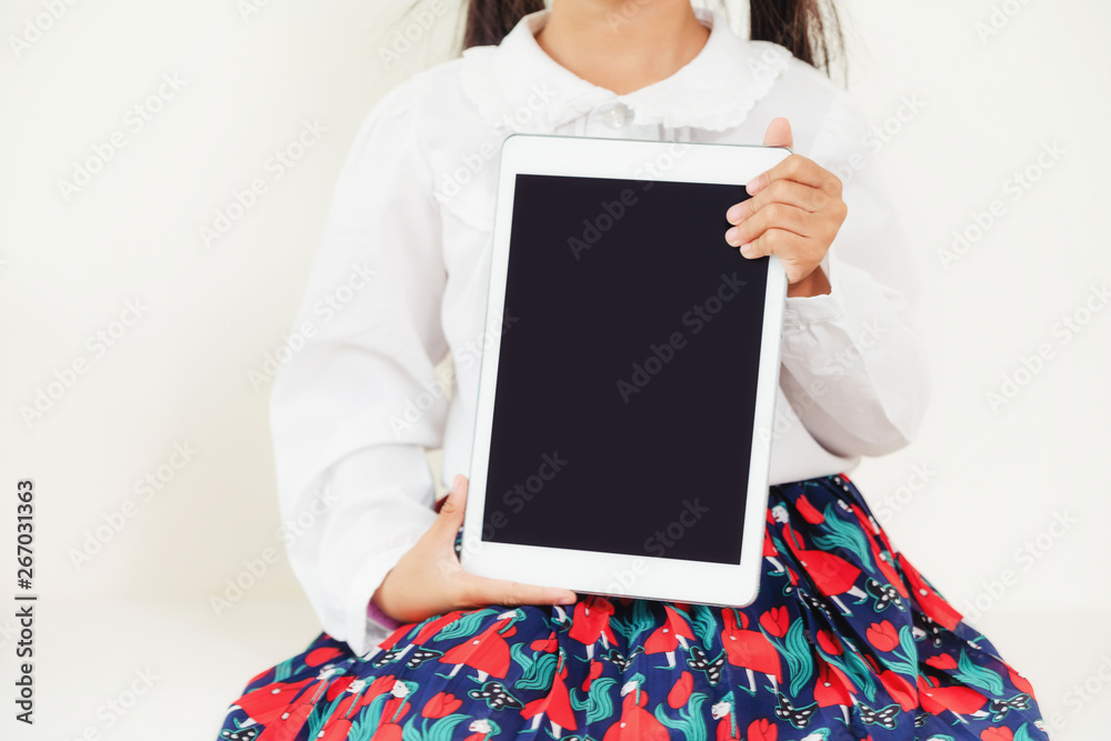 Little kid showing black screen of tablet computer on white background.