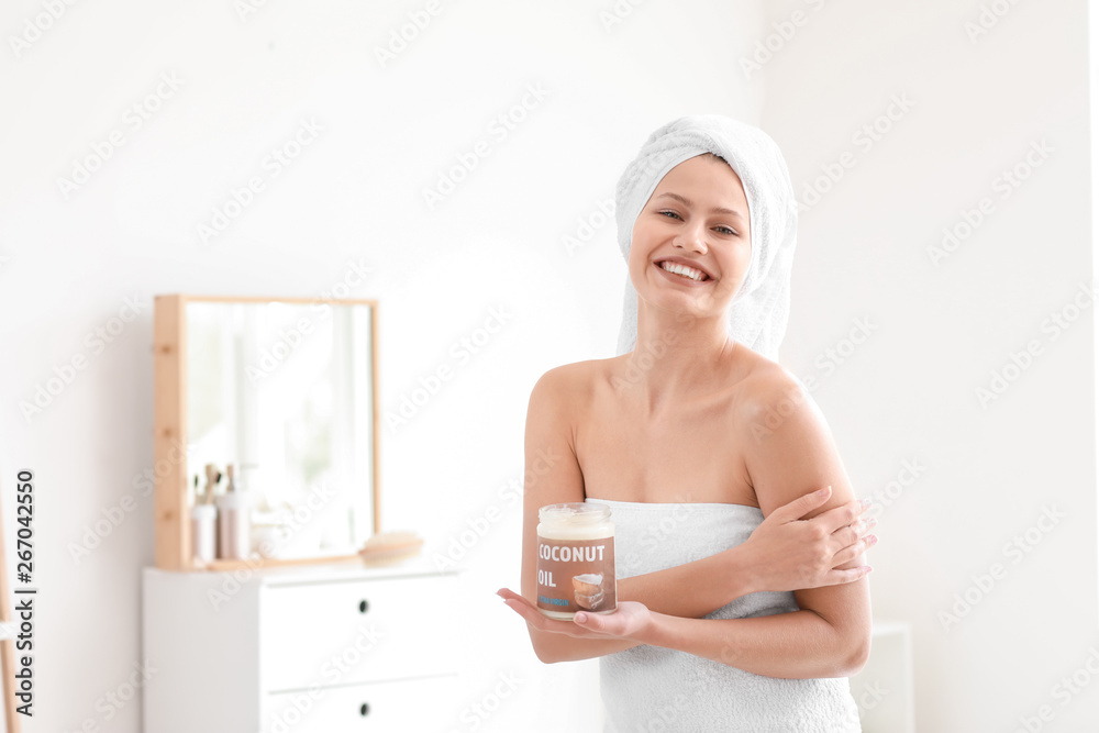 Beautiful young woman applying coconut oil at home