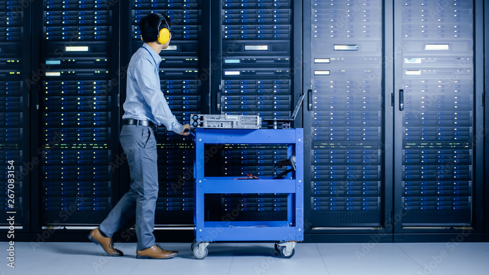 In the Modern Data Center: IT Engineer Doing Maintenance and Diagnostics. Pushes Cart alongside Serv