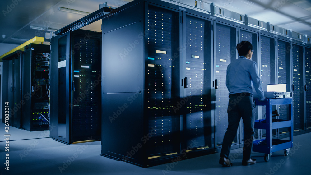 In the Modern Data Center: IT Engineer Doing Maintenance and Diagnostics. Pushes Cart alongside Serv