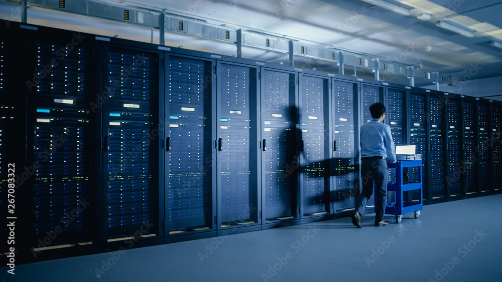 In the Modern Data Center: IT Engineer Doing Maintenance and Diagnostics. Pushes Cart alongside Serv