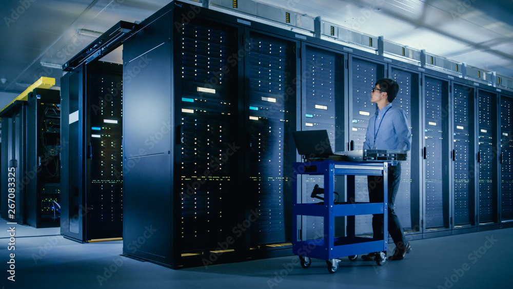 In the Modern Data Center: IT Engineer Doing Maintenance and Diagnostics. Pushes Cart alongside Serv