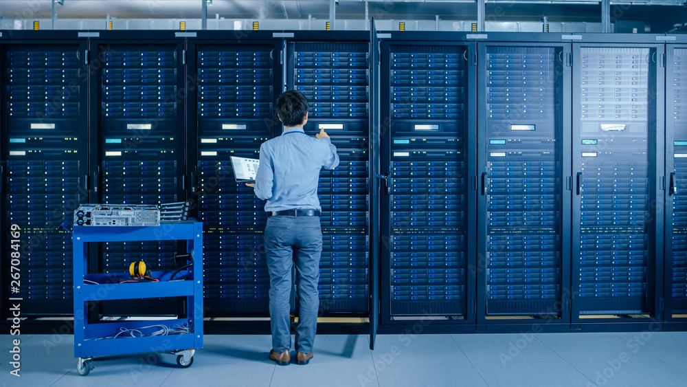 In the Modern Data Center: IT Engineer Doing Maintenance and Diagnostics. Works with Opened Cabinet 