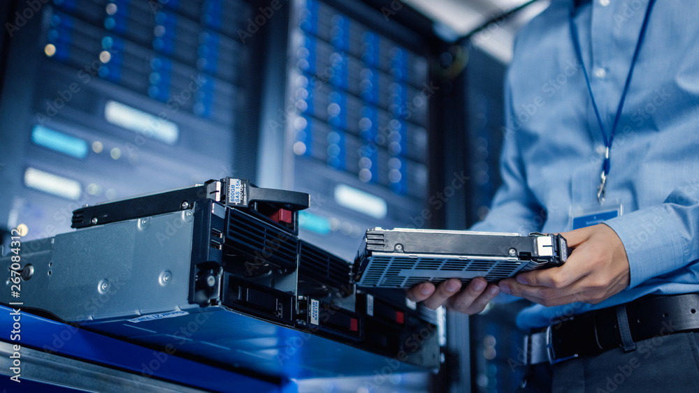 In the Modern Data Center: IT Engineer is Holding New HDD Hard Drive Prepared for Installing Hardwar