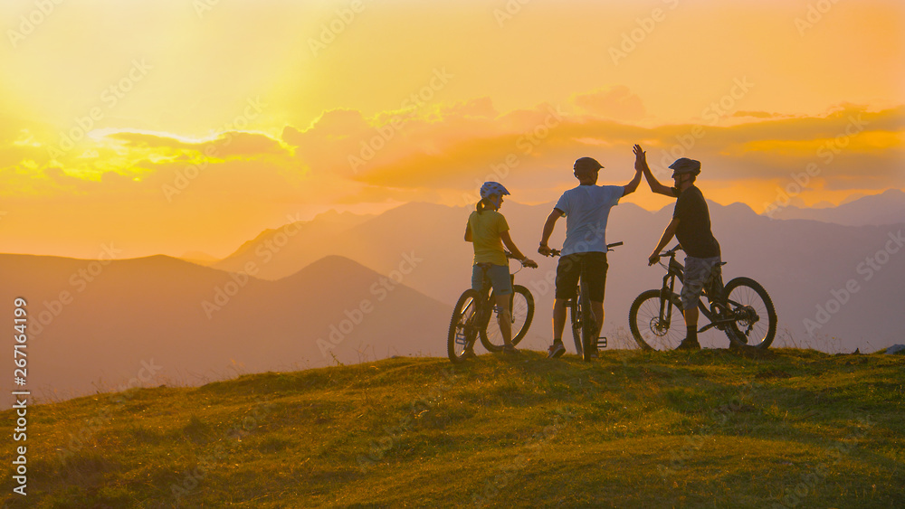 Unrecognizable sporty tourists high five after a successful evening bike ride.