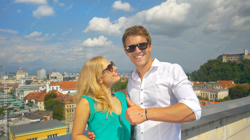 PORTRAIT: Cheerful woman poses with her handsome boyfriend giving the thumbs up.