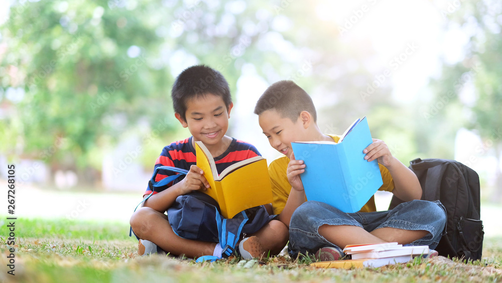 Two boys of primary reading and doing homework together.