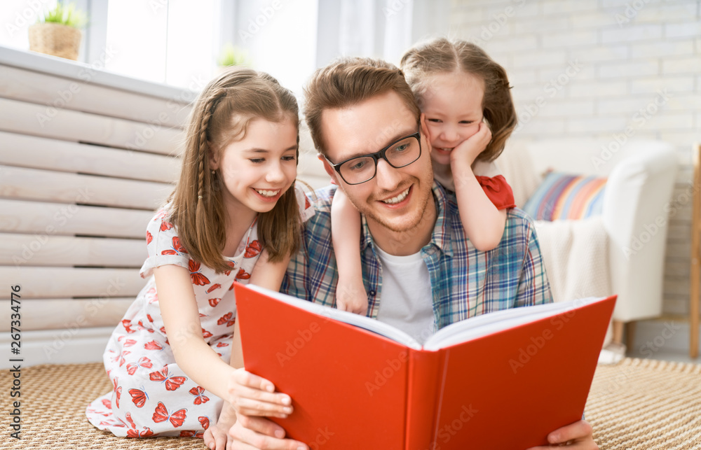 father reading a book to his daughters