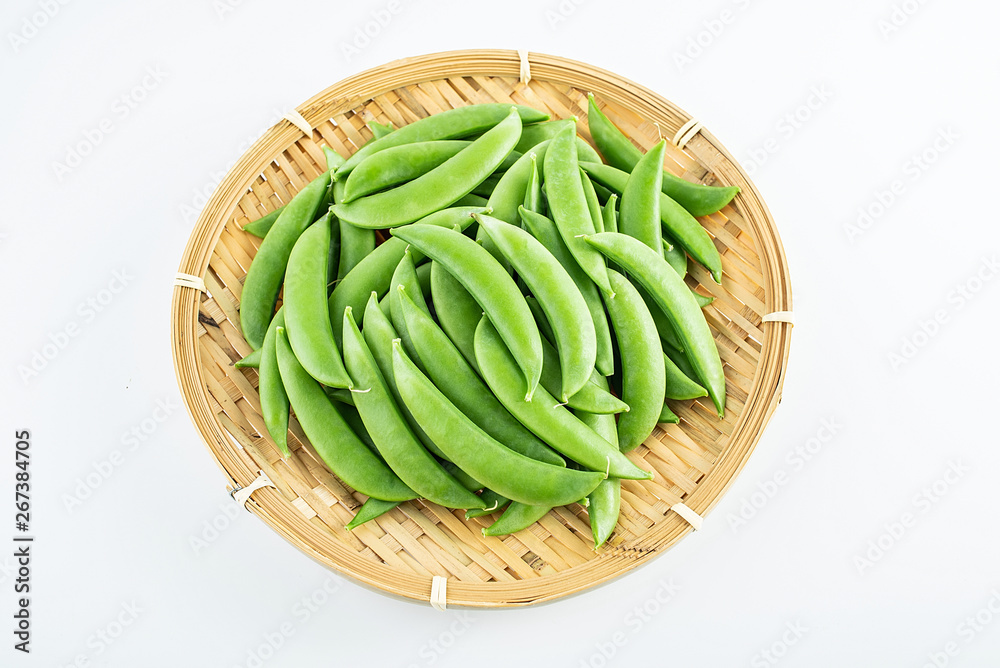 A bamboo sieve fresh pods vegetables sweet beans on a white background